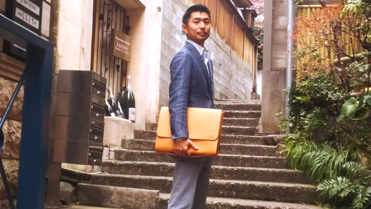 神楽坂で革のクラッチバッグを持つ大滝さん